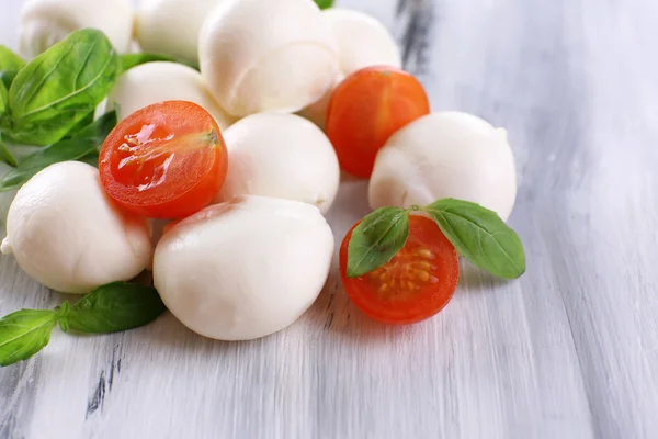 Tasty mozzarella cheese with basil and tomatoes, on wooden table — Stock Photo, Image
