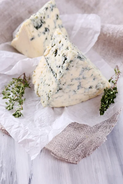 Smakelijke blauwe kaas met tijm op papier — Stockfoto