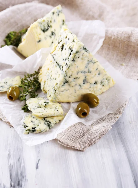 Queijo azul saboroso com tomilho e azeitonas em papel — Fotografia de Stock