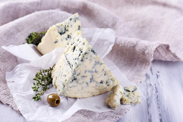 Tasty blue cheese with thyme and olives on paper — Stock Photo, Image