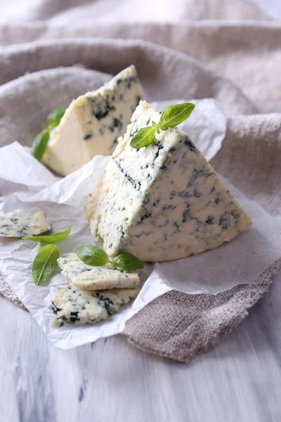 Tasty blue cheese with basil on paper — Stock Photo, Image