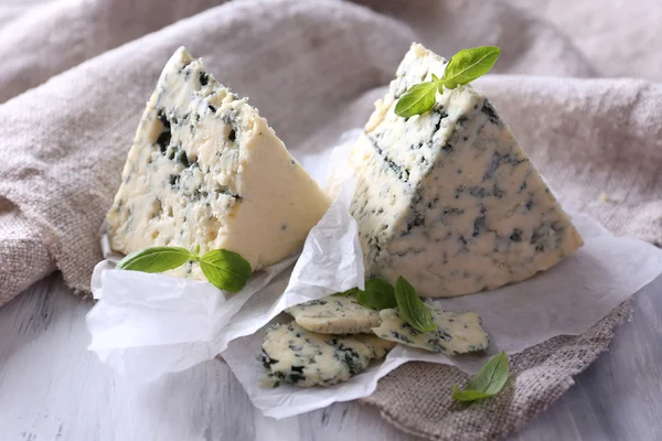 Queijo azul saboroso com manjericão sobre papel — Fotografia de Stock