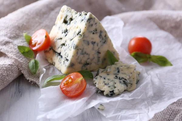 Queijo azul saboroso com tomate e manjericão sobre papel — Fotografia de Stock