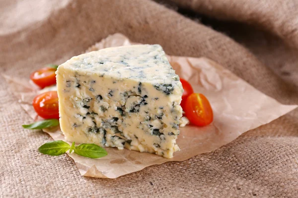 Smakelijke blauwe kaas met tomaten en basilicum, op jute achtergrond — Stockfoto