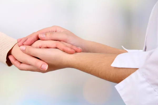 Medico che tiene la mano del paziente, su sfondo chiaro — Foto Stock