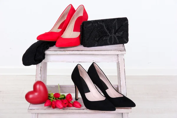 Hermosos zapatos femeninos negros y rojos, bolso y flores sobre fondo blanco —  Fotos de Stock