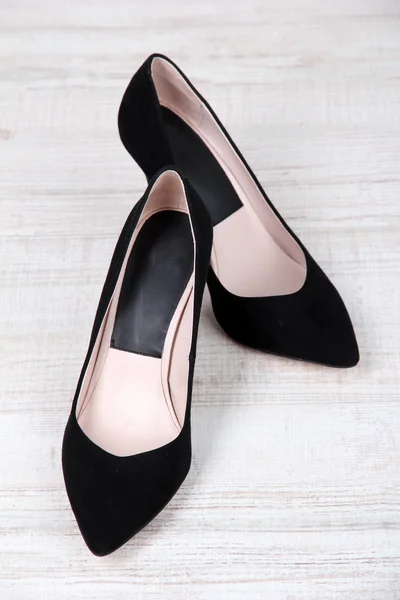 Mooie zwarte vrouwelijke schoenen op houten achtergrond — Stockfoto