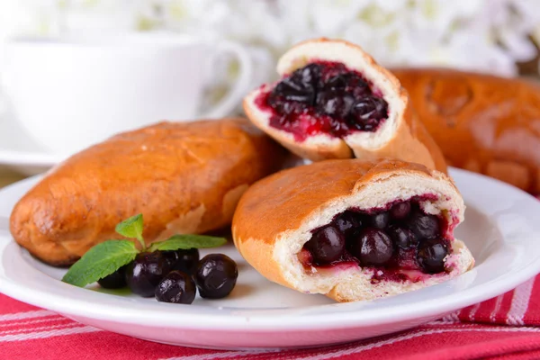 Fresh baked pasties with currant on plate on table close-up — Stock Photo, Image