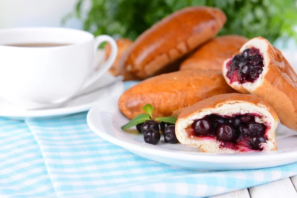 Fresh baked pasties with currant on plate on table close-up — Stock Photo, Image