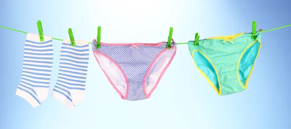 Babykleidung hängt an der Wäscheleine, auf hellem Hintergrund — Stockfoto
