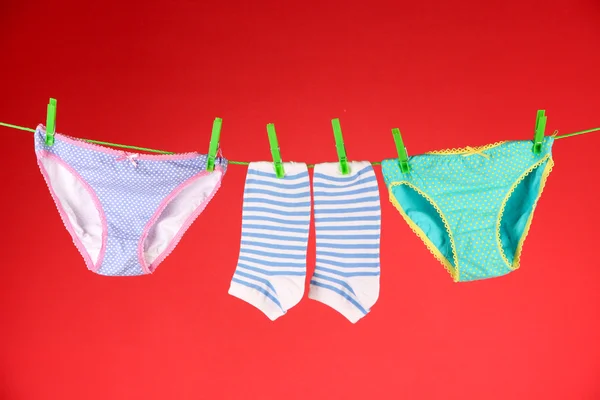 Baby clothes hanging on clothesline, on color background — Stock Photo, Image