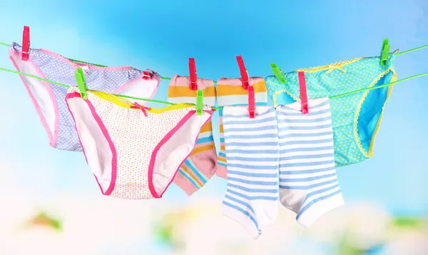 Vestiti per bambini appesi alla clothesline, su sfondo luminoso — Foto Stock