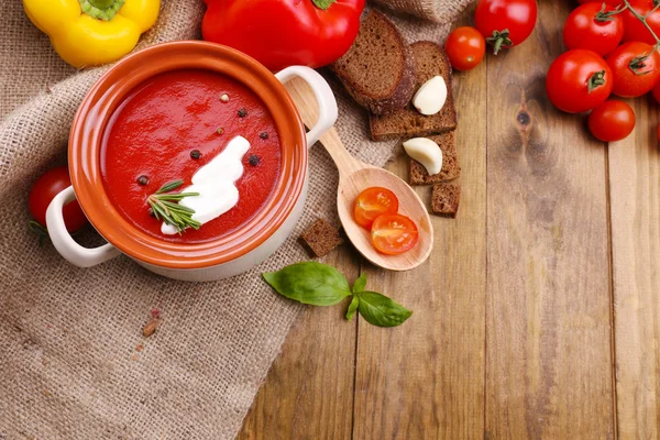 Tasty tomato soup and vegetables on wooden table — Stockfoto