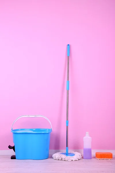 Golv mopp och hink för tvätt i rum på rosa vägg bakgrund — Stockfoto