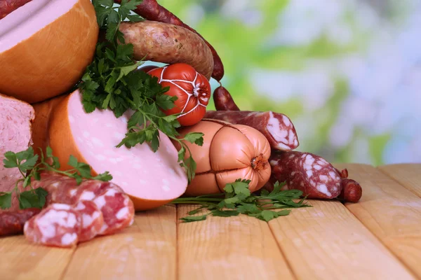 Veel verschillende worstjes op houten tafel op natuurlijke achtergrond — Stockfoto