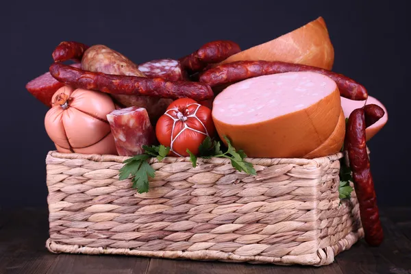 Lote de salsichas diferentes em cesta na mesa de madeira no fundo preto — Fotografia de Stock