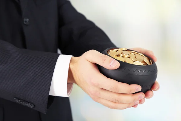 Ceramic pot with golden coins in male hands, on light background — Stock Photo, Image