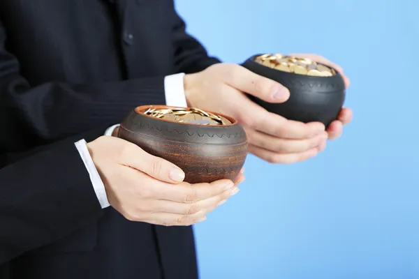 Two ceramic pots with golden coins in male and female hands, on color background — Stock Photo, Image