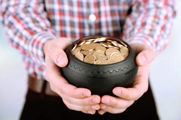 Ceramic pot with golden coins in male hands, on light background — Stock Photo, Image