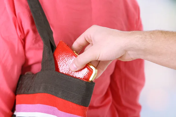 El carterista está robando la cartera de la bolsa, de cerca, sobre un fondo claro — Foto de Stock