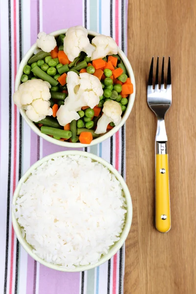 Kokt ris med grönsaker på träbord — Stockfoto