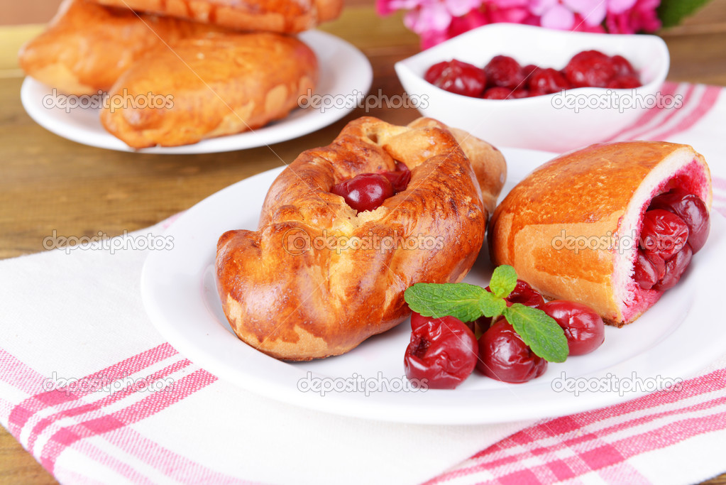 Fresh baked pasties with cherry on plate on table close-up