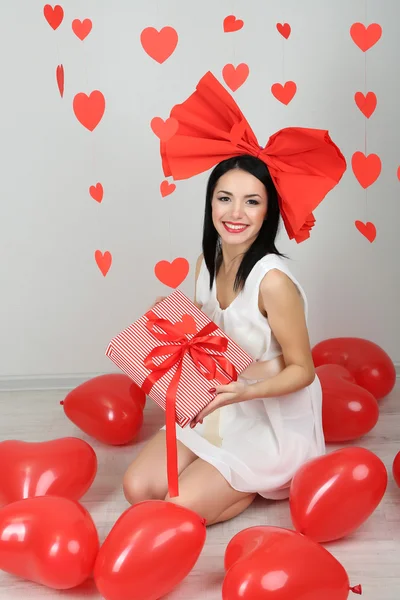 Attraente giovane donna con regalo e palloncini in camera a San Valentino — Foto Stock