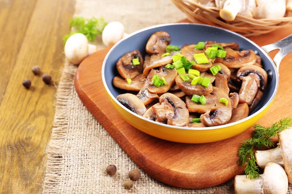 Deliciosos cogumelos fritos na panela na mesa close-up — Fotografia de Stock