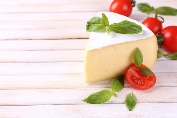 Queijo saboroso Camembert com manjericão e tomate, sobre mesa de madeira — Fotografia de Stock