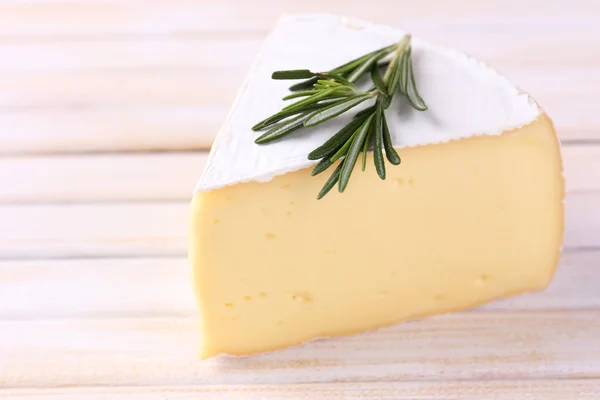 Tasty Camembert cheese with rosemary, on wooden table — Stock Photo, Image
