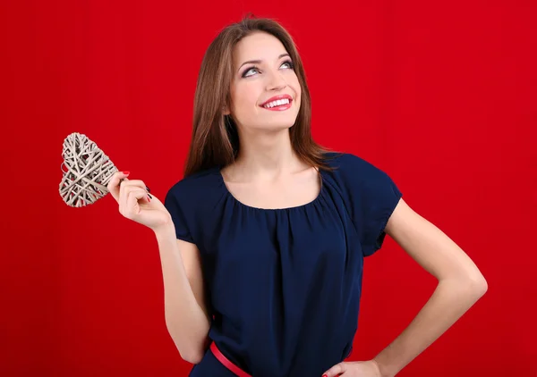 Attraktive Frau mit Weidenherz, auf rotem Hintergrund — Stockfoto
