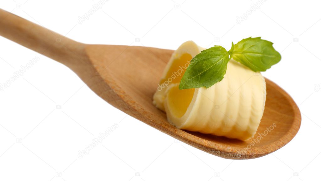Curl of fresh butter with basil on wooden spoon, isolated on white