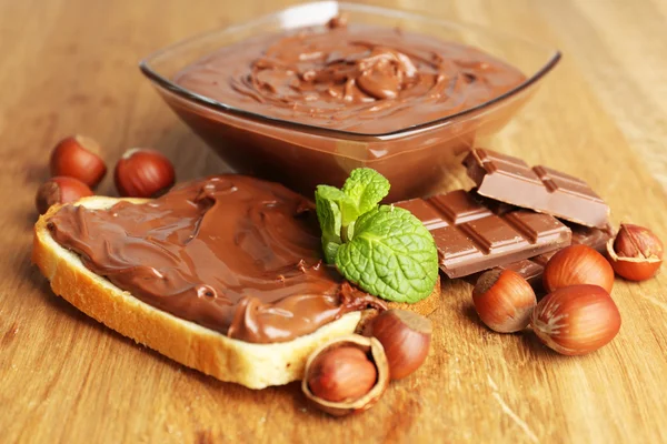 Chléb s sladká čokoláda lískových spread na dřevěné pozadí — Stock fotografie