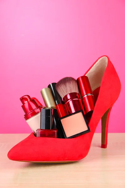 Vackra röda kvinnliga sko med kosmetika, på rosa bakgrund — Stockfoto