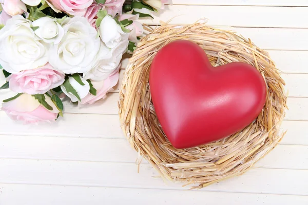 Coeur décoratif dans le nid, sur fond en bois couleur — Photo