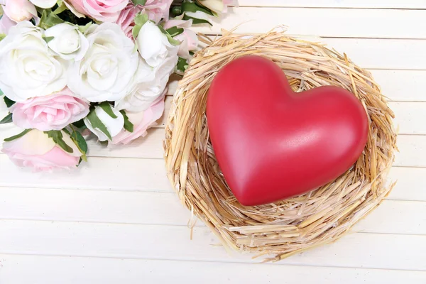 Decorative heart in nest, on color wooden background — Stock Photo, Image