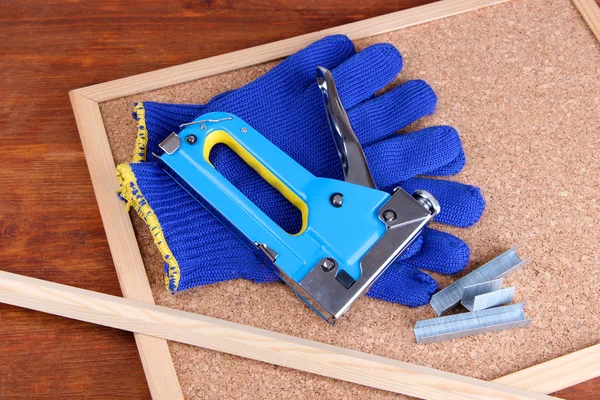 Grampeador de construção com luvas e grampos na placa de cortiça de perto — Fotografia de Stock