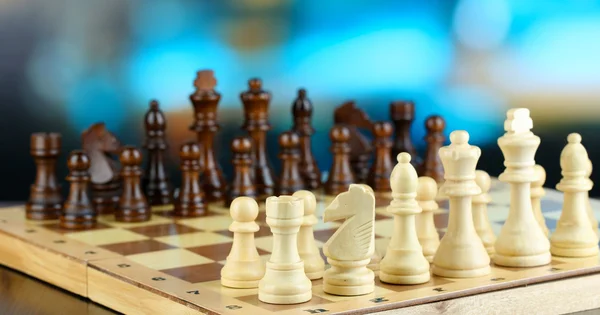 Schachfiguren an Bord auf hellem Hintergrund — Stockfoto