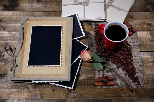 Композиция с чашкой кофе и фотоальбомом, на деревянном фоне — стоковое фото