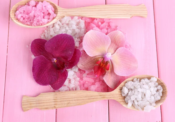 Stilleven met prachtige bloeiende orchidee bloem en houten lepels met zeezout, op een houten achtergrond kleur — Stockfoto
