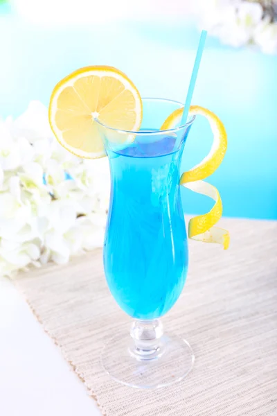 Glass of cocktail on table on light blue background — Stock Photo, Image