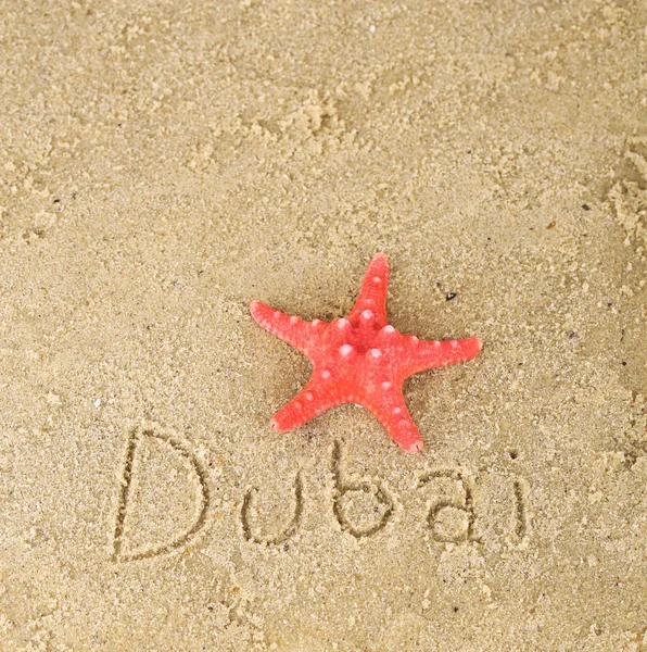 Inscription Dubai in wet sand close-up background — Stock Photo, Image