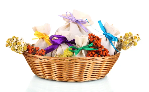 Textile sachet pouches with dried flowers, herbs and berries in wicker basket, isolated on white — Stock Photo, Image