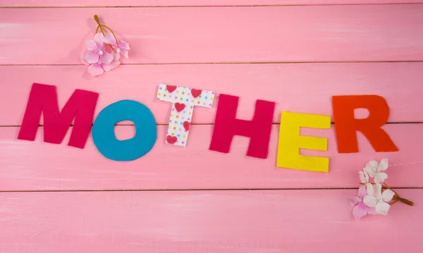 Mother- lettering of handmade paper letters on pink wooden background — Stock Photo, Image