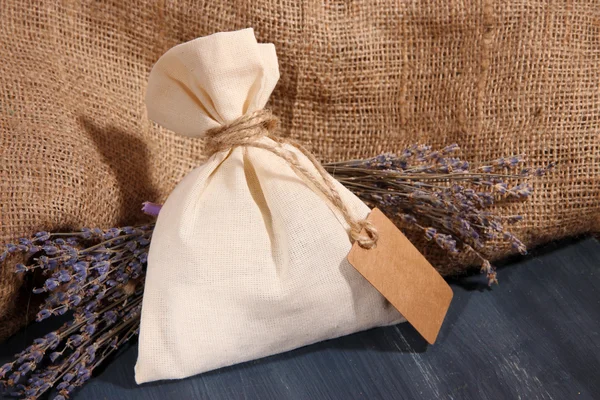 Textilní sáček sáček s květy sušené levandule na dřevěný stůl, na pozadí pytloviny — Stock fotografie