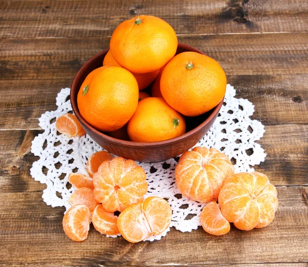 Спелые сладкие мандарины со специями в миске, на салфетке, на деревянном фоне — стоковое фото