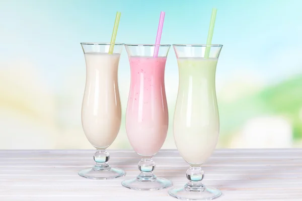 Milk shakes on table on light blue background — Stock Photo, Image