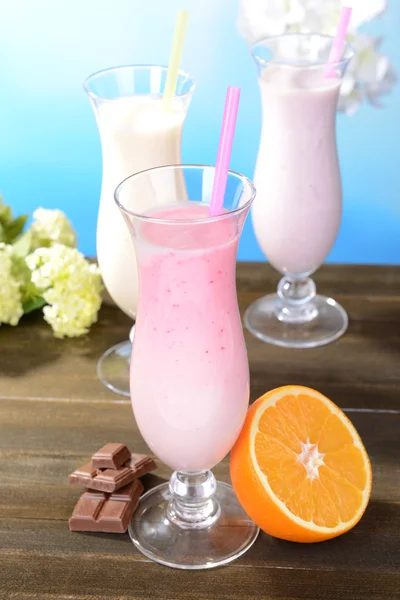 Batidos de leite com frutas na mesa no fundo azul claro — Fotografia de Stock