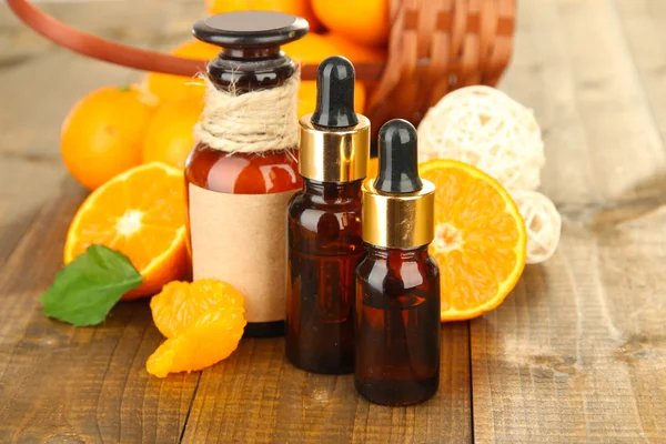 Aceite esencial de mandarina y mandarinas sobre mesa de madera — Foto de Stock