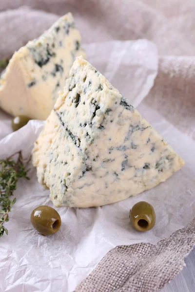 Sabroso queso azul con tomillo y aceitunas sobre papel — Foto de Stock
